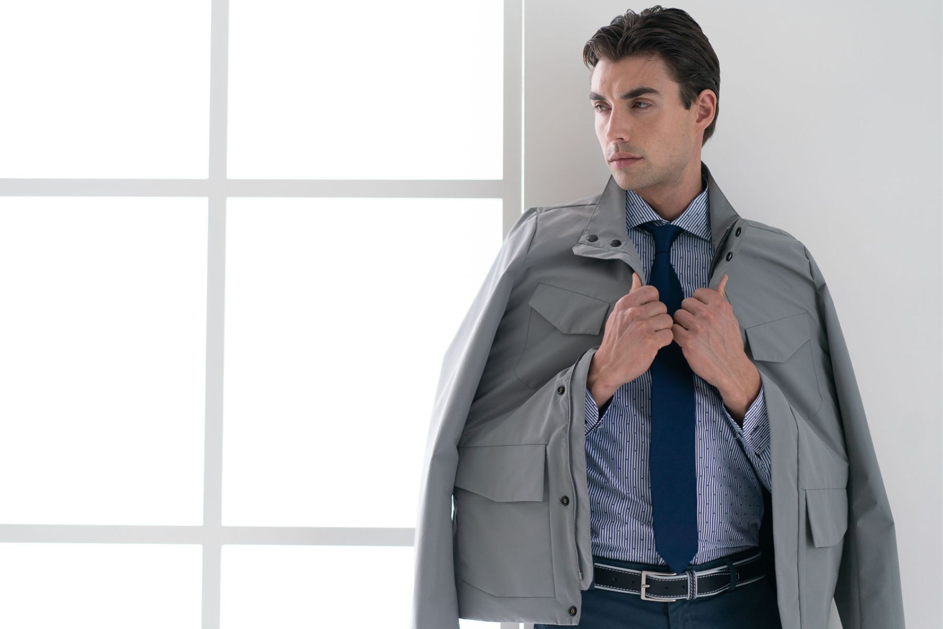 ragazzo con giubbino field jacket grigio, camicia fil coupé e cravatta